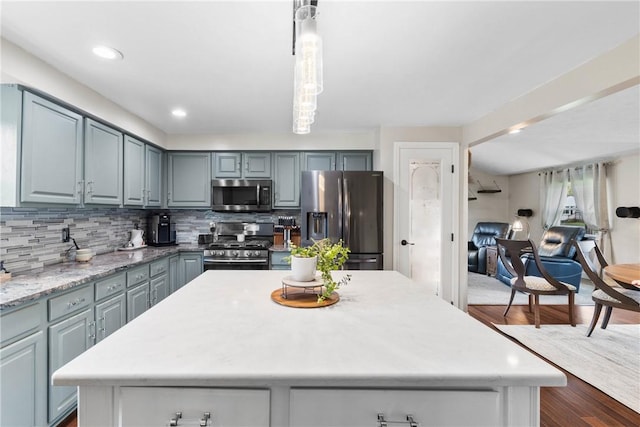 kitchen with stainless steel appliances, gray cabinets, backsplash, dark wood-style floors, and a center island