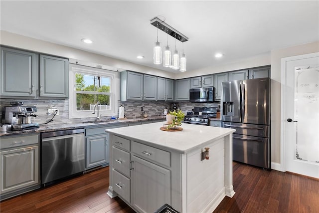 kitchen featuring appliances with stainless steel finishes, gray cabinets, a sink, dark wood finished floors, and backsplash