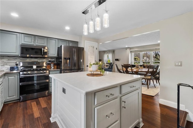 kitchen featuring stainless steel appliances, backsplash, dark wood-style flooring, light countertops, and gray cabinetry