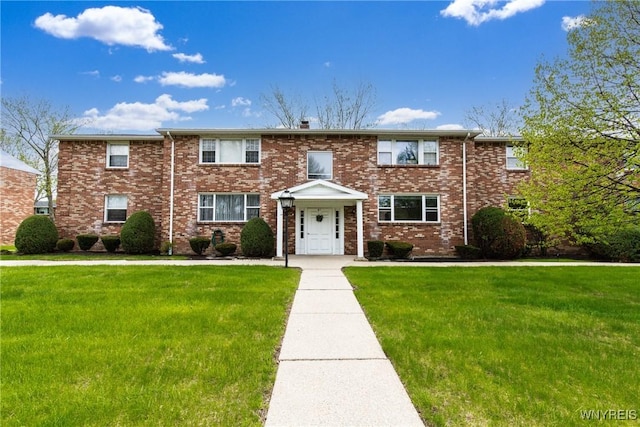 multi unit property with a front yard, brick siding, and a chimney