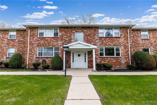 view of property with a front lawn and brick siding