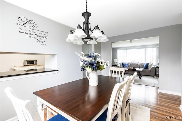 dining room with a chandelier, wood finished floors, and baseboards