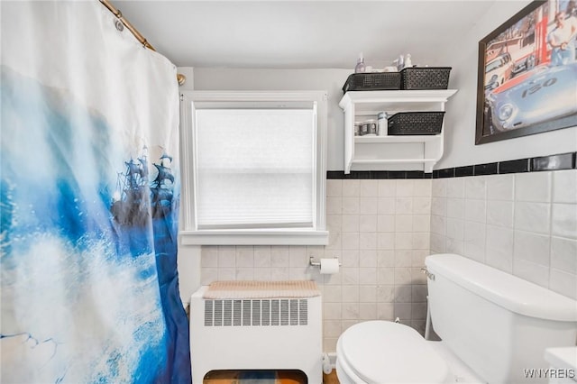 bathroom with radiator, toilet, tile walls, and curtained shower