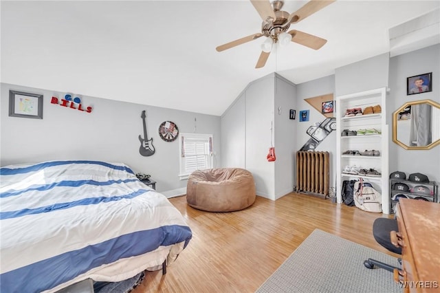 bedroom featuring radiator, wood finished floors, lofted ceiling, and a ceiling fan