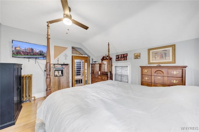 bedroom with radiator, vaulted ceiling, light wood finished floors, ceiling fan, and baseboards