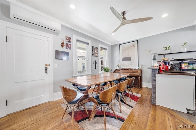 dining area with a wall mounted AC, light wood-type flooring, crown molding, a ceiling fan, and baseboards
