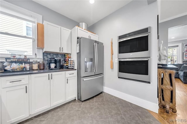 kitchen with stainless steel appliances, dark countertops, white cabinetry, tile patterned floors, and recessed lighting