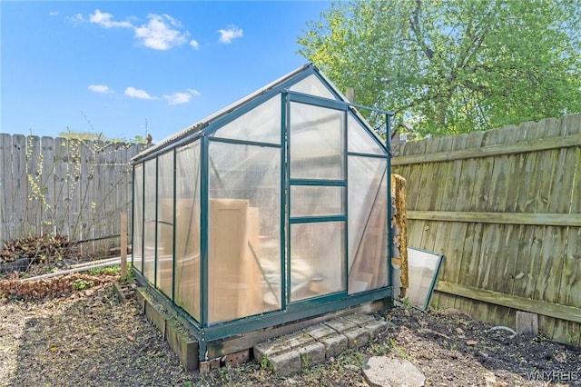 view of greenhouse featuring a fenced backyard