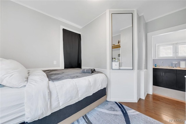 bedroom featuring crown molding, a sink, and wood finished floors