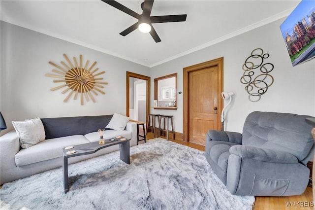 living area with ceiling fan, wood finished floors, and crown molding