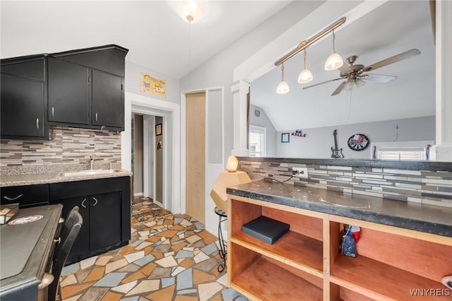 kitchen with dark cabinetry, lofted ceiling, a sink, tasteful backsplash, and a ceiling fan