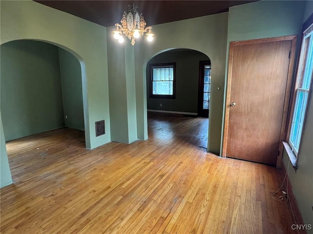 1270 W Belden Ave, Syracuse, NY 13204 - empty room with hardwood / wood-style flooring, arched walkways, and a chandelier