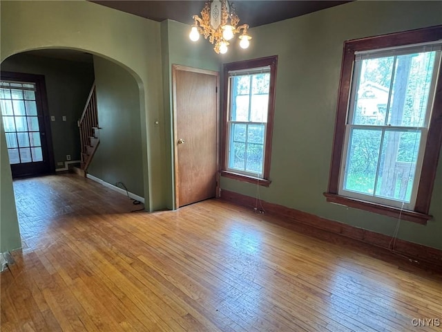 1270 W Belden Ave, Syracuse, NY 13204 - spare room with light wood-style flooring, arched walkways, stairs, a chandelier, and baseboards