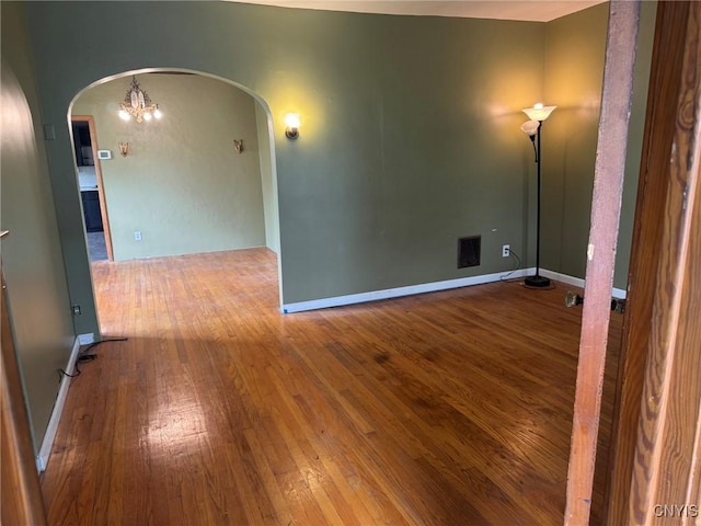 1270 W Belden Ave, Syracuse, NY 13204 - spare room with arched walkways, wood-type flooring, and a chandelier