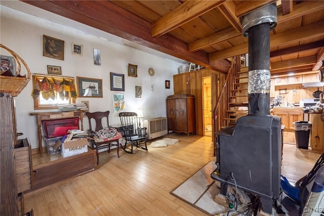 living area with a wood stove, hardwood / wood-style flooring, beam ceiling, wood ceiling, and radiator heating unit