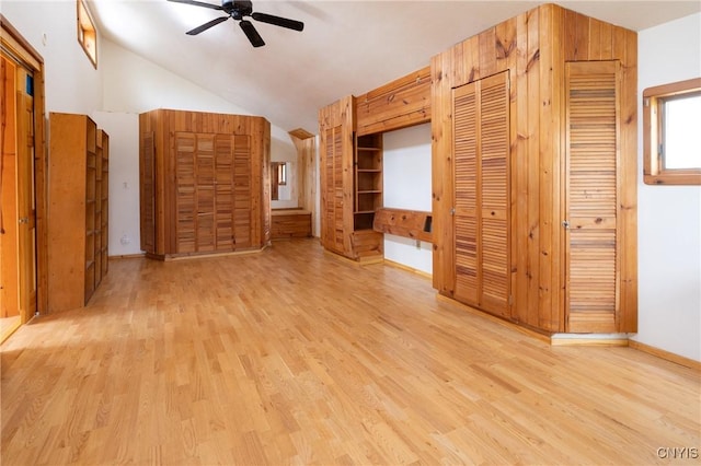 unfurnished bedroom featuring light wood-type flooring, vaulted ceiling, a ceiling fan, multiple closets, and baseboards