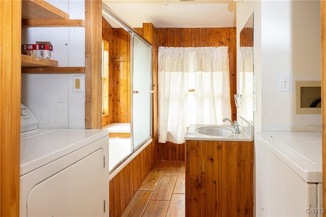 full bath with washing machine and clothes dryer, hardwood / wood-style floors, vanity, a tub, and wooden walls