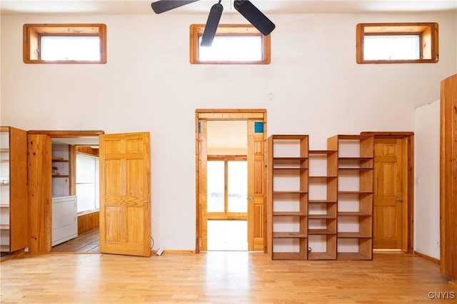 interior space featuring ceiling fan, washer / clothes dryer, wood finished floors, a towering ceiling, and healthy amount of natural light