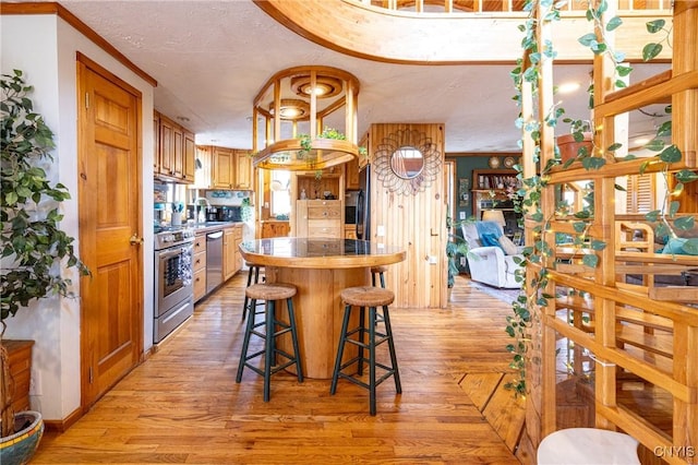 kitchen featuring stainless steel appliances, light wood-type flooring, a sink, a kitchen bar, and a kitchen island