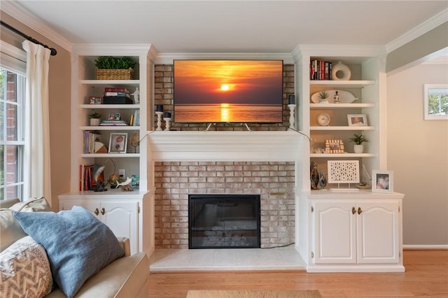 living area with light wood-type flooring, crown molding, a brick fireplace, and built in shelves