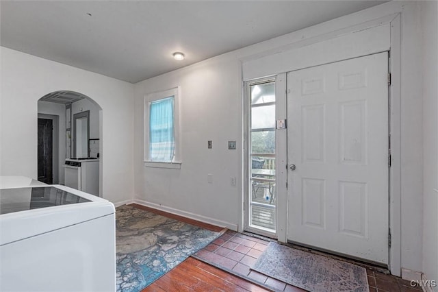 foyer with arched walkways, wood finished floors, washer / clothes dryer, and baseboards