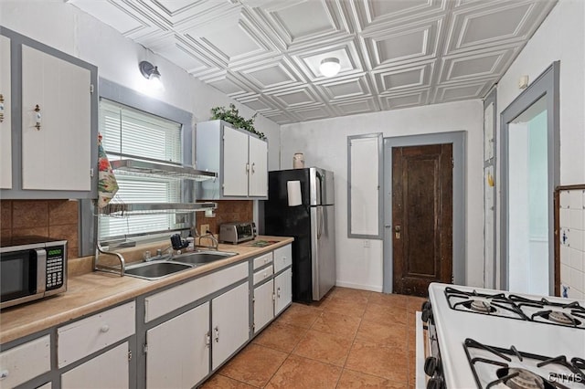 kitchen with stainless steel appliances, a sink, an ornate ceiling, light countertops, and tasteful backsplash