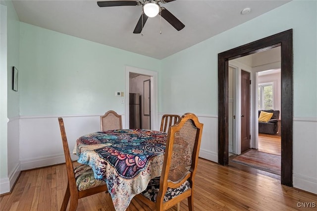 dining room featuring light wood-style floors, a ceiling fan, and baseboards