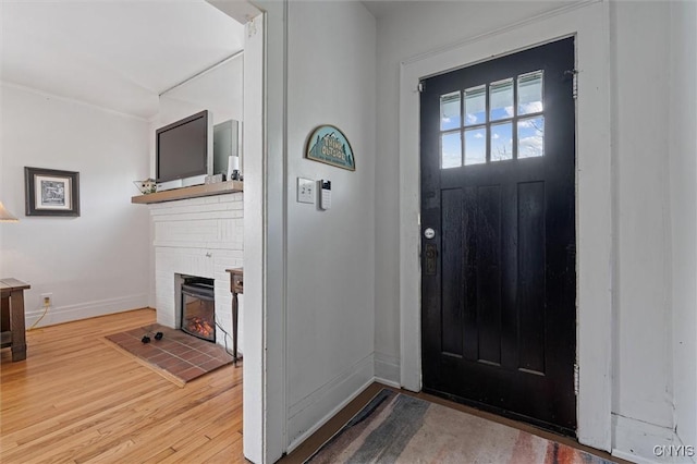 entryway with a brick fireplace, baseboards, and wood finished floors