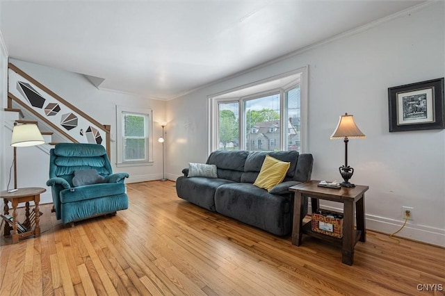 living area featuring light wood finished floors, stairway, crown molding, and baseboards