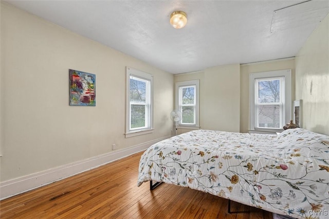 bedroom with wood-type flooring, baseboards, and multiple windows