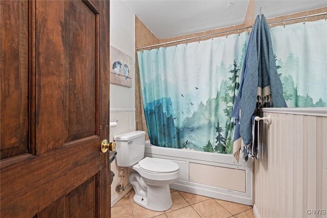 bathroom featuring tile patterned floors, toilet, shower / tub combo, and wainscoting