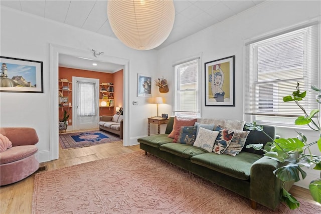 living room with wood finished floors, crown molding, and baseboards