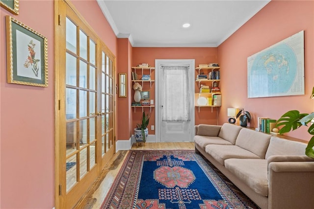 living area with wood finished floors, ornamental molding, french doors, and baseboards