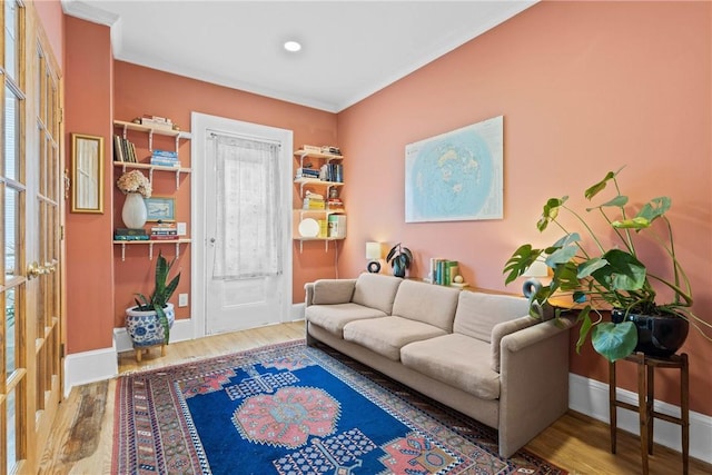 sitting room featuring wood finished floors, ornamental molding, and baseboards