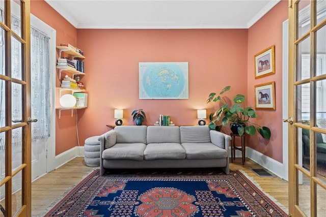 sitting room featuring french doors, ornamental molding, wood finished floors, and baseboards