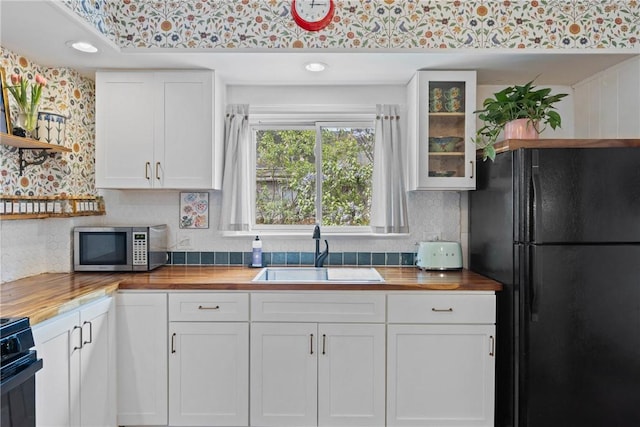 kitchen featuring wood counters, freestanding refrigerator, a sink, open shelves, and stainless steel microwave