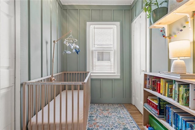 interior space featuring a decorative wall, wood finished floors, and a nursery area