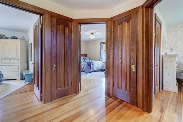 hall with light wood-type flooring and wallpapered walls