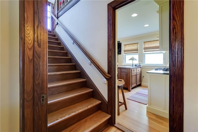 stairs featuring wood finished floors and recessed lighting