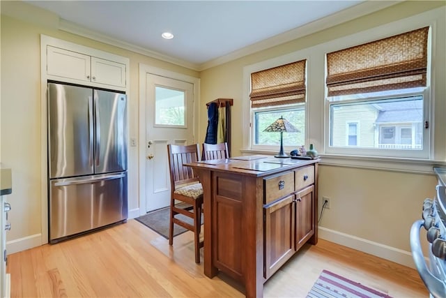 kitchen with appliances with stainless steel finishes, light wood finished floors, baseboards, crown molding, and brown cabinets