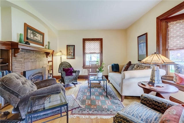 living area featuring a brick fireplace, wood finished floors, and baseboards