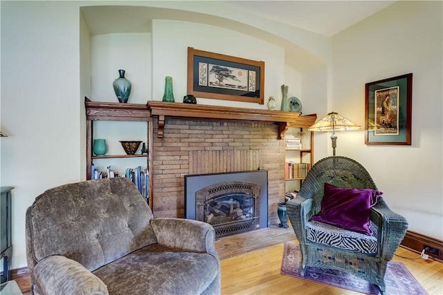 sitting room with wood finished floors, a fireplace, and baseboards