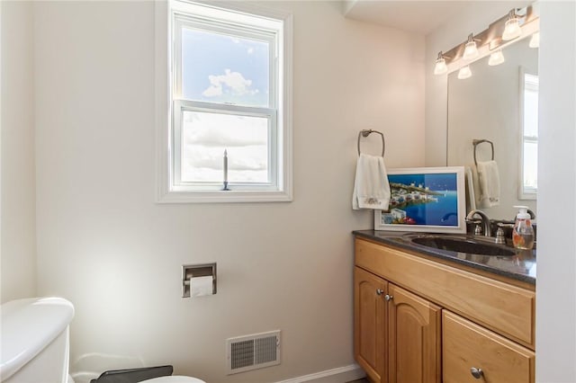 half bath with toilet, vanity, and baseboards