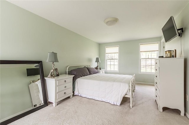 bedroom with light colored carpet and baseboards