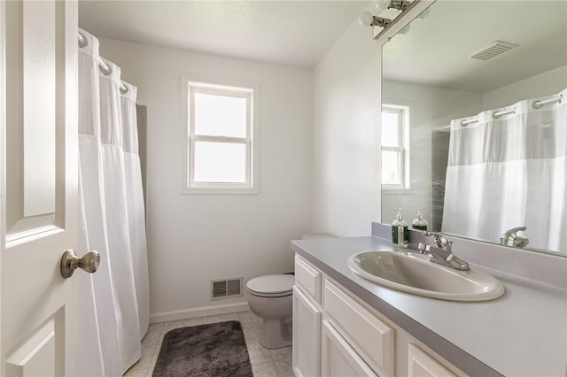 bathroom with toilet, vanity, tile patterned flooring, and baseboards