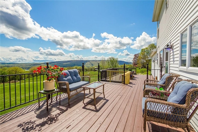 wooden terrace with an outdoor hangout area, a yard, and a mountain view