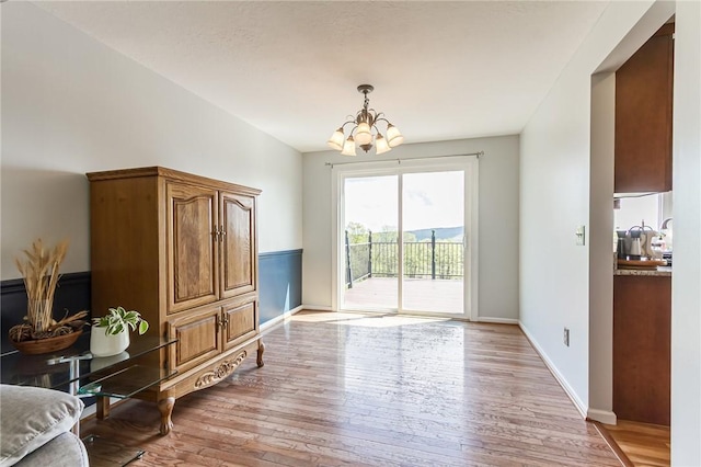 doorway to outside with a chandelier, light wood-style floors, and baseboards