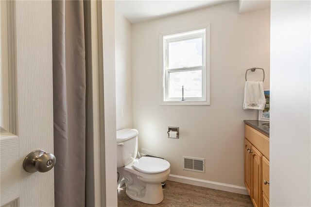 bathroom featuring toilet, vanity, baseboards, and wood finished floors