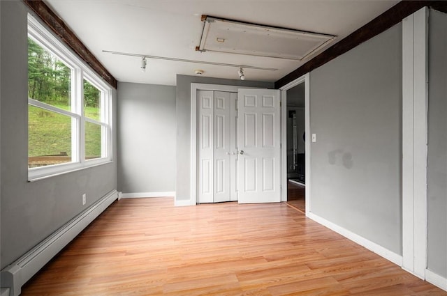 7471 State Highway 80, Springfield, NY 13326 - unfurnished bedroom featuring baseboard heating, track lighting, light wood-style flooring, and baseboards
