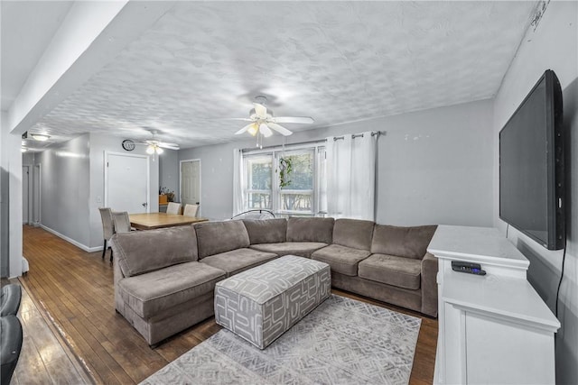 living room featuring ceiling fan, wood-type flooring, baseboards, and a textured ceiling